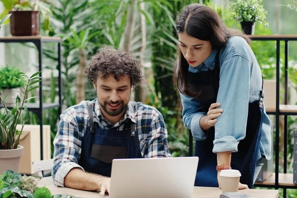 Two people working together on a laptop outdoors